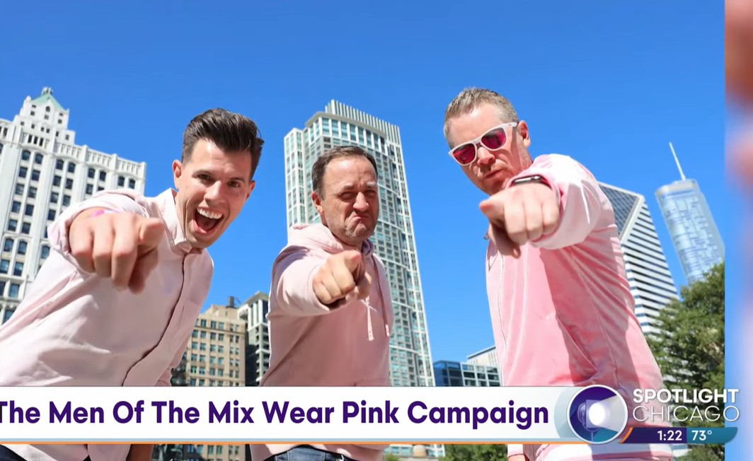 Three men wearing pink pointing at the camera